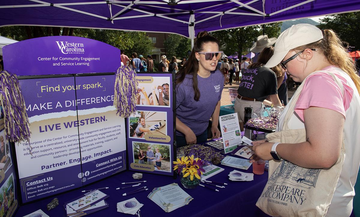 Student handing out pamphlets to visitors and other students at a stand