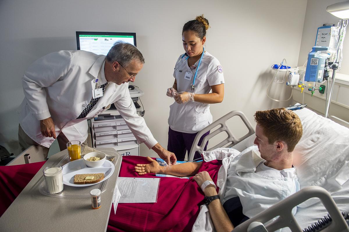 Dr. and nurse student attend to a patient in their hospital bed