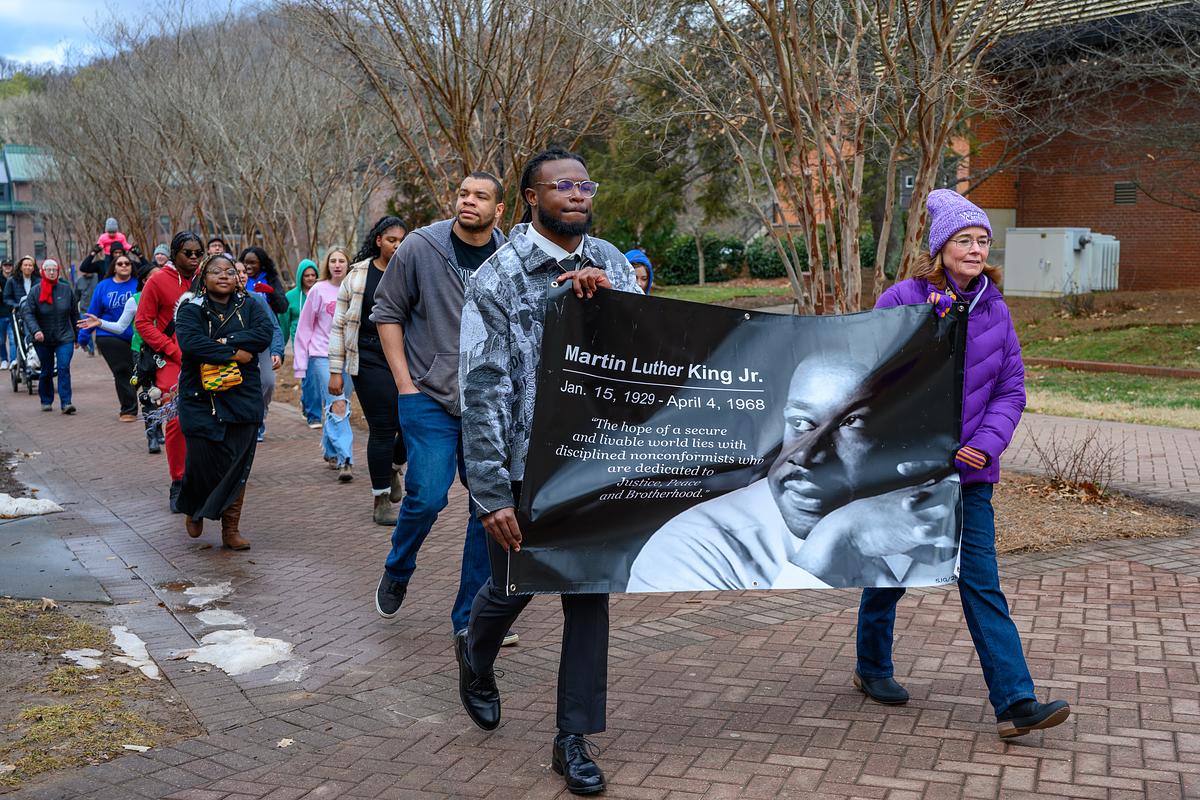 Students marching together with the chancelor holding up a Martin Luther King Jr. sign in the MLK March