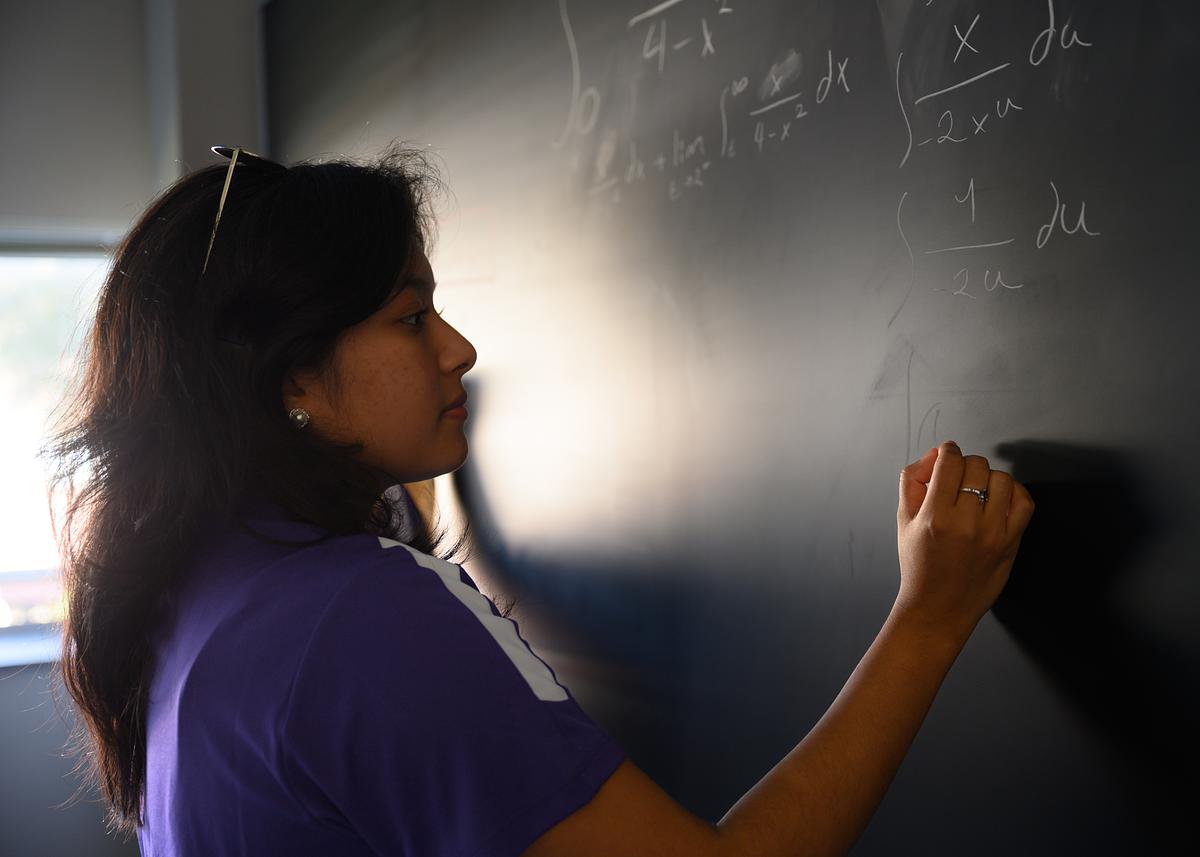 Noyce program member writing a math equation on a chalkboard 