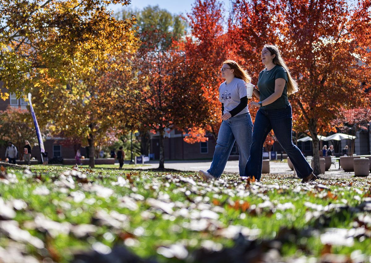 Two students walking on campus in the fall