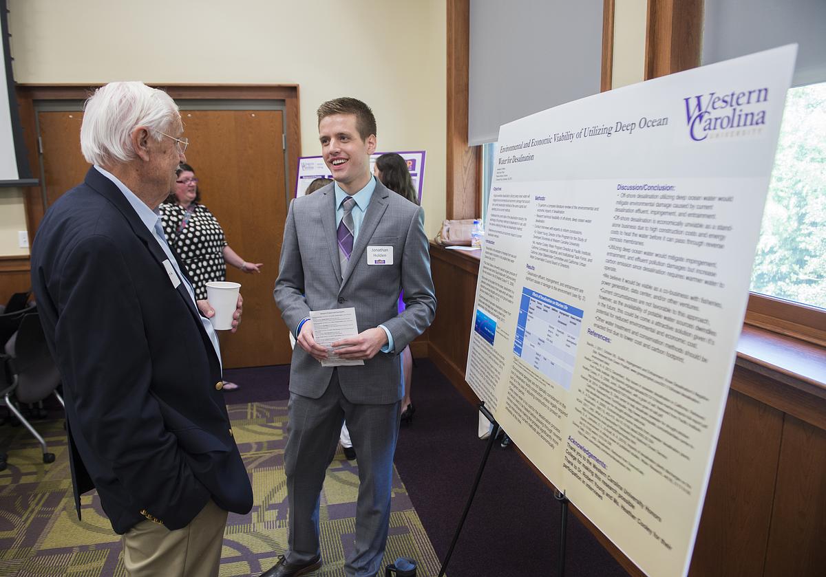 Undergraduate research student showing their work to an audience member