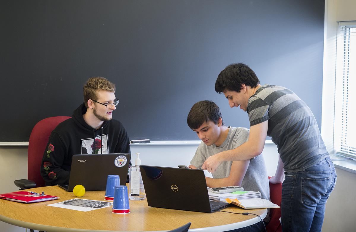 Math students sitting around at a table discussing equation solutions