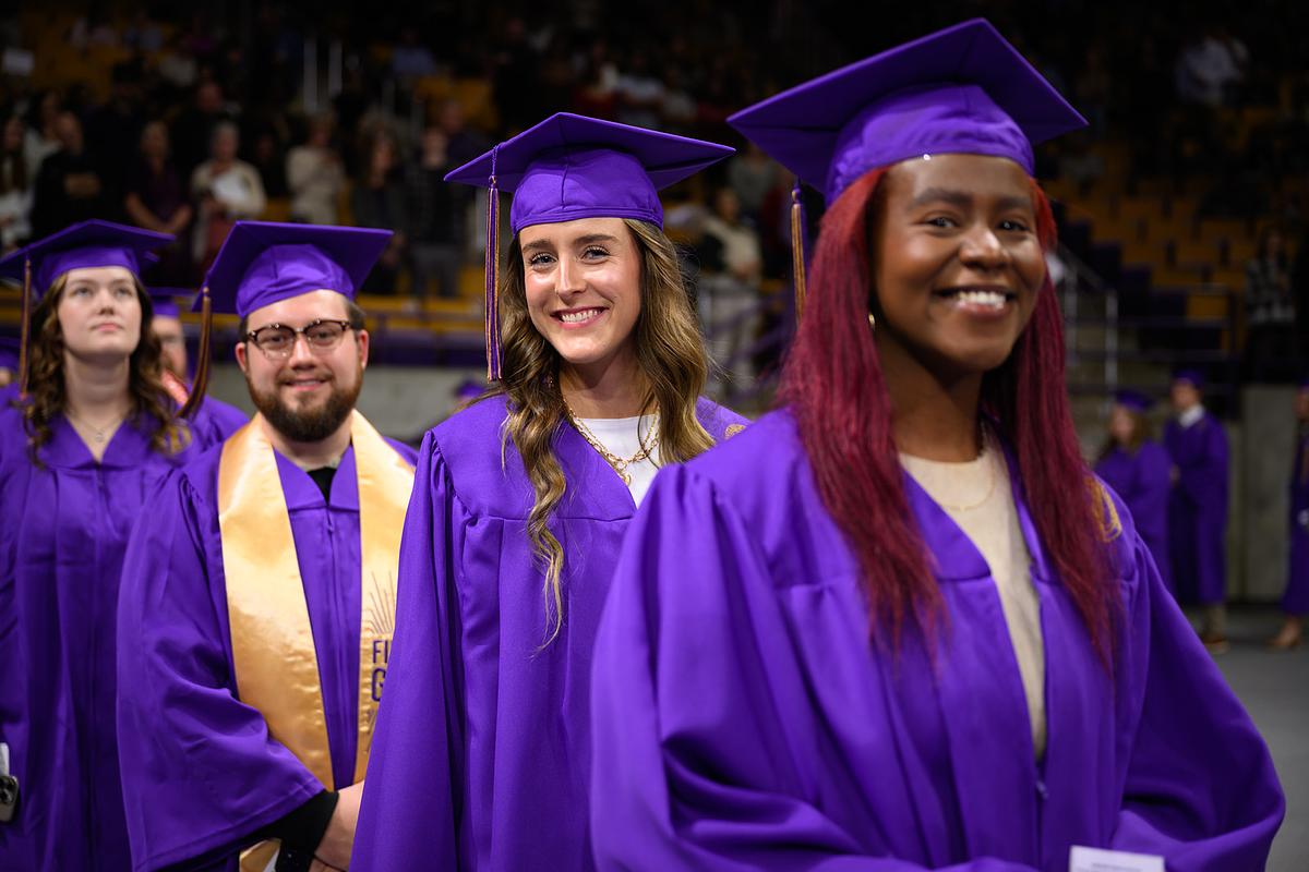 Graduating students at commencement smiling for the camera