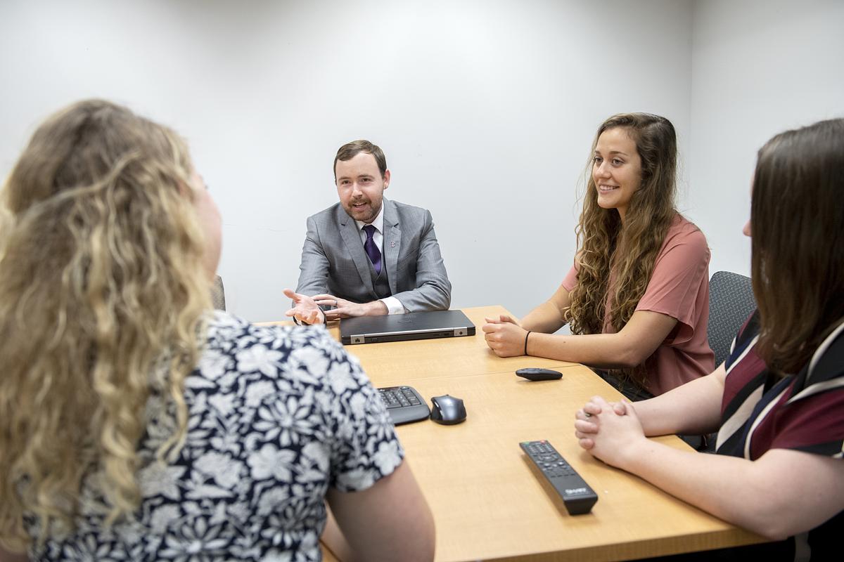Psychology graduate students and professor David Solomon sitting around a table in discussion
