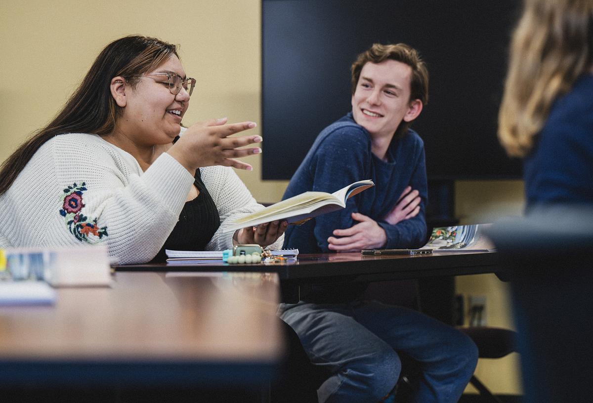 Student looking out the window smiling as they study