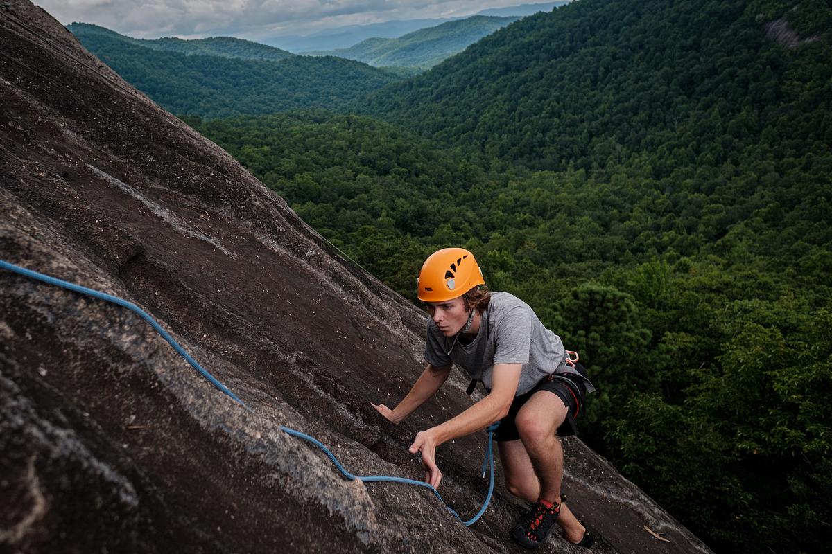 Student reaching the top of a rock face