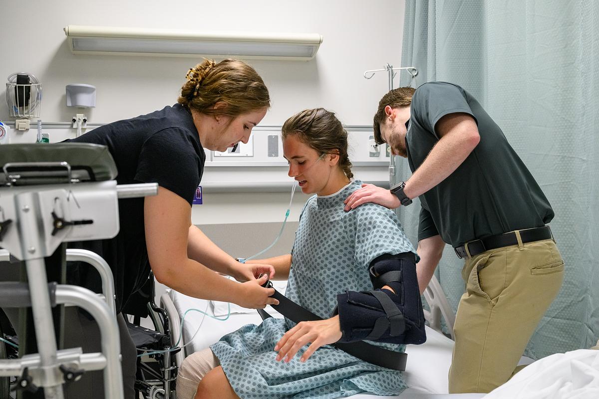 Student nurses helping a patient get out of their hospital bed