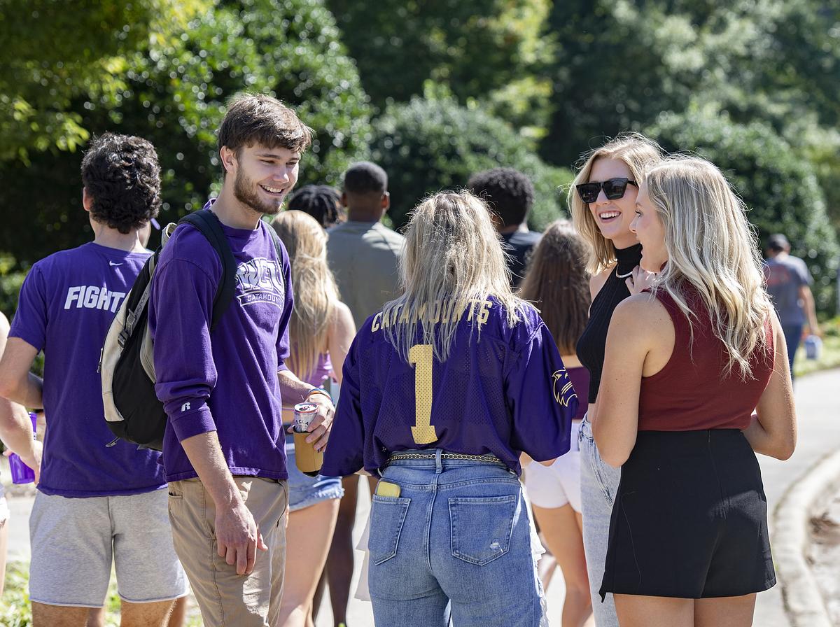 Students gathered together smiling and talking outside at the homecoming tailgate