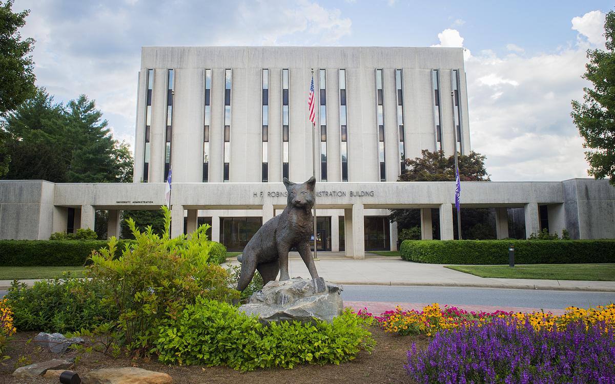 Student outside at a table working on their computer on a beautiful fall day
