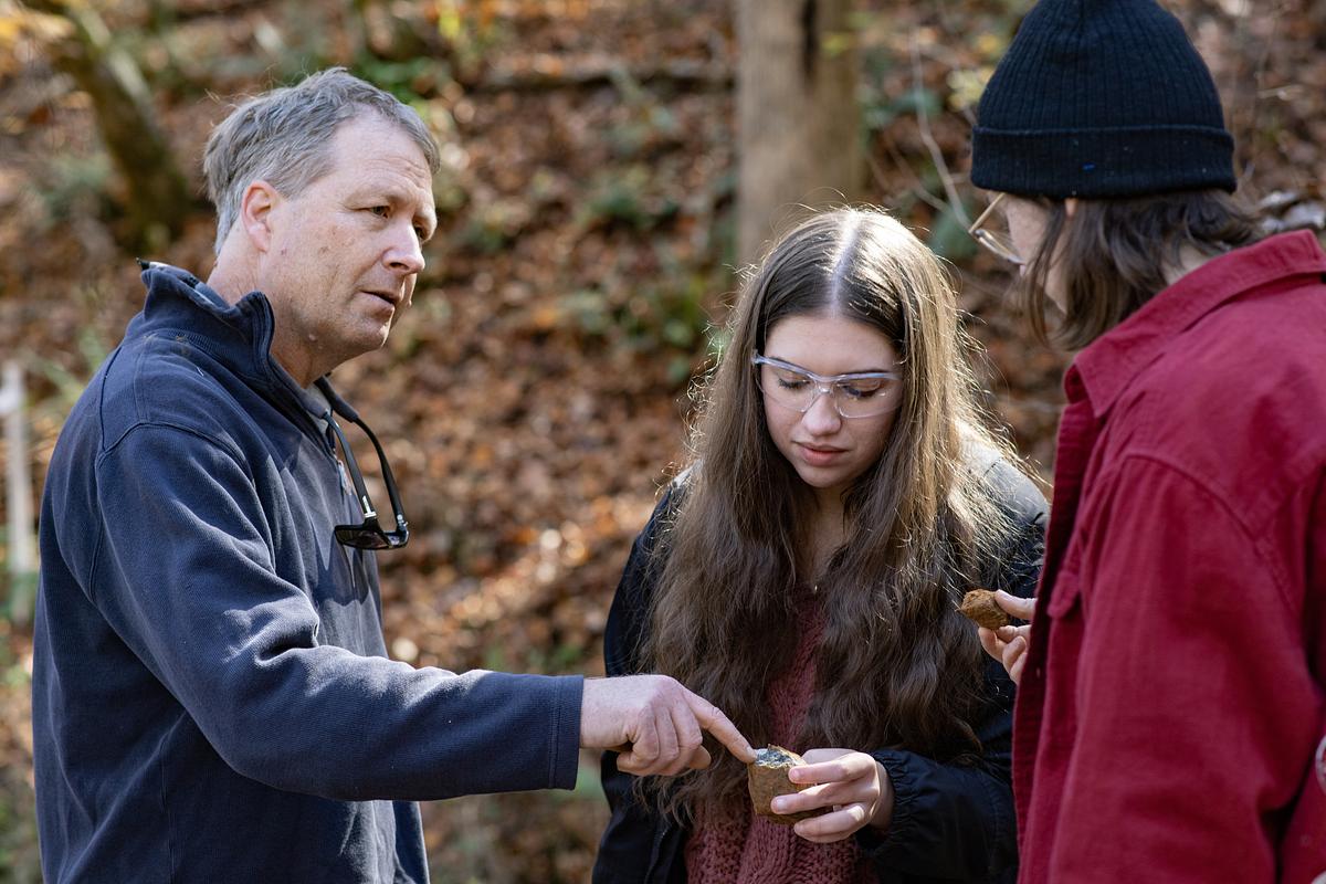 Instructor looking at a rock with students