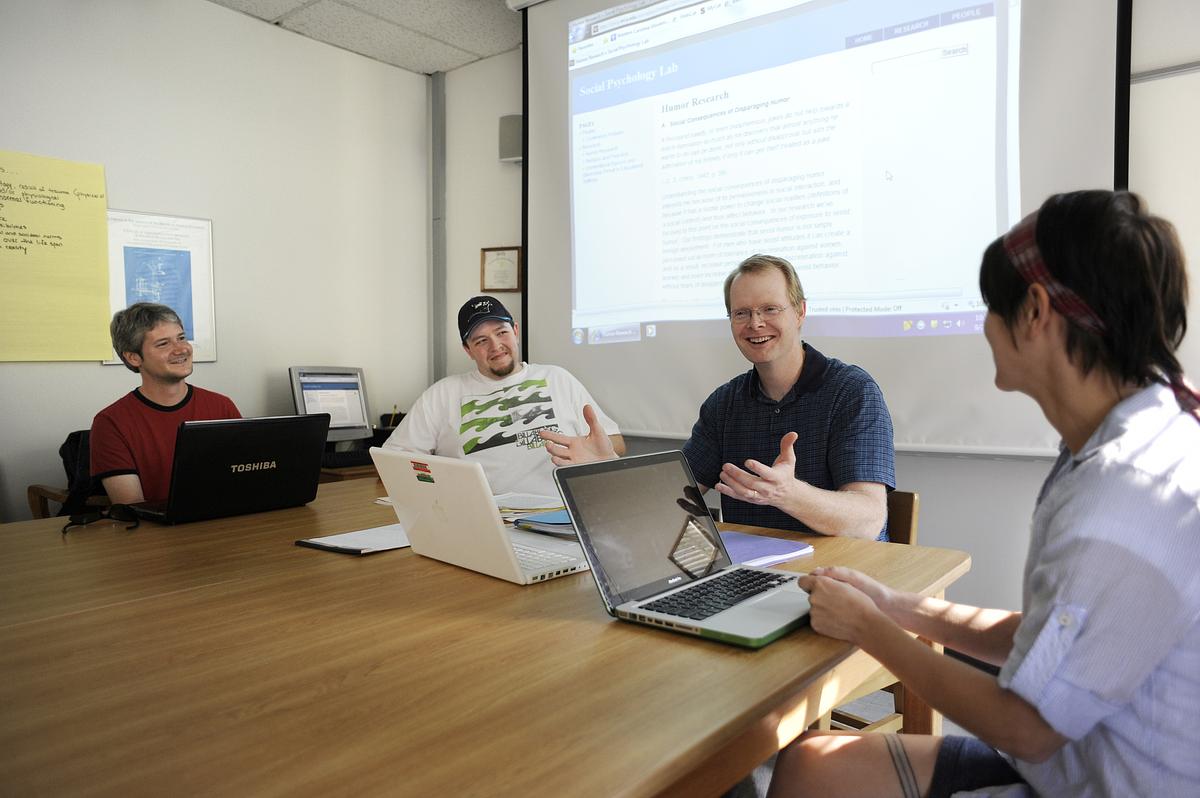 Professor talking with his students in a classroom around a table