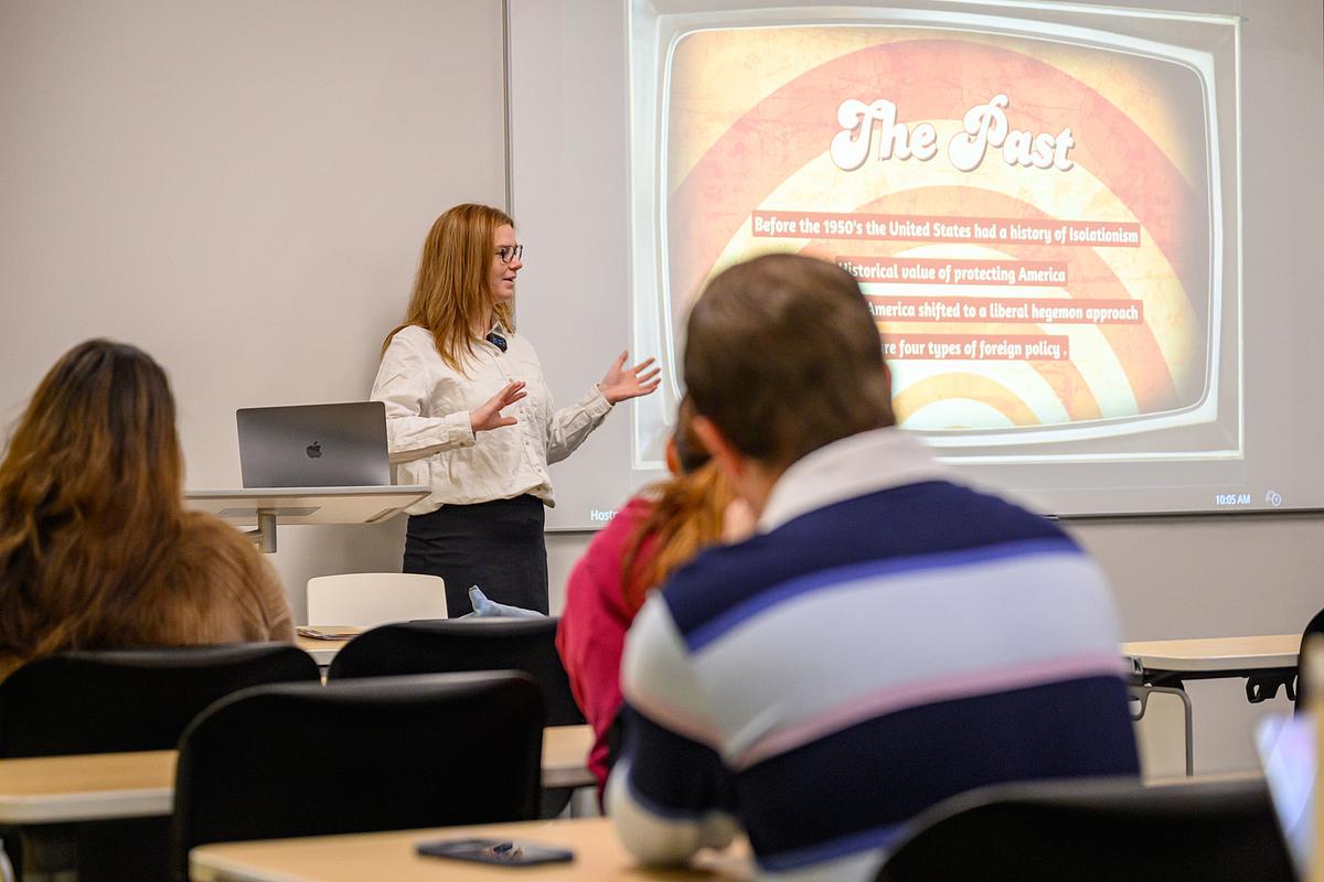 Professor giving a lecture to a class with a powerpoint presentation