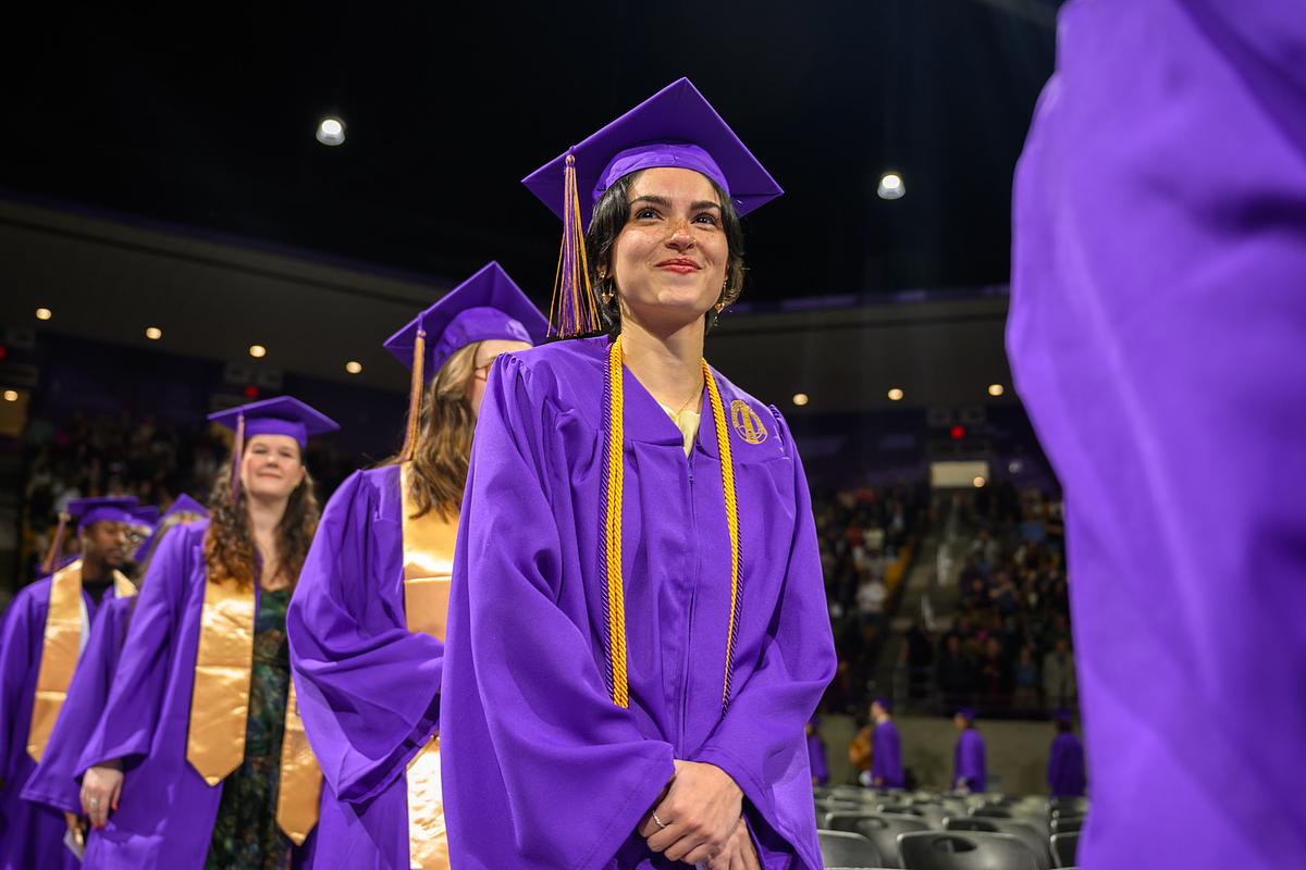 Graduate student smiling as they walk to receive their degree