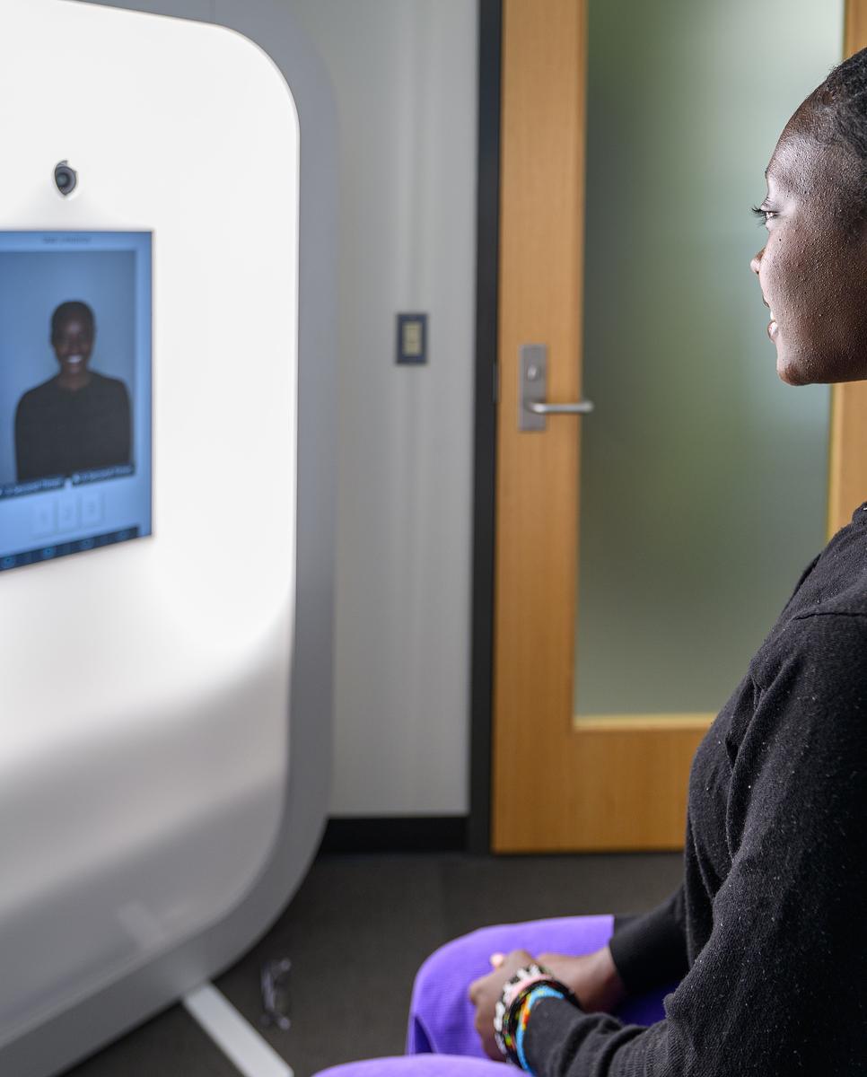 Young woman sitting in a chair facing a photobooth for a picture
