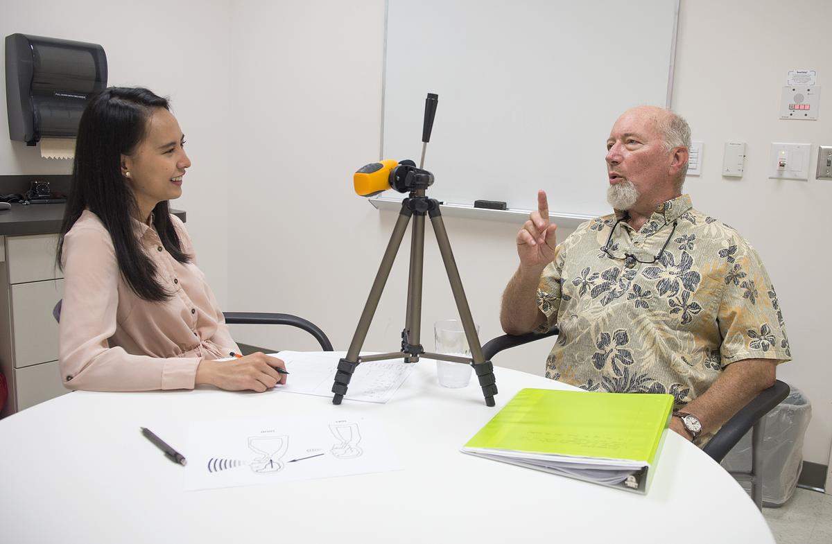 Student and patient sitting around a table with audio equipment for the communications science disorders program