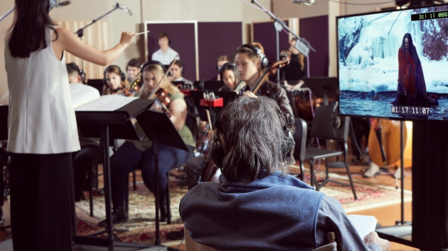 An orchestra performs a film score with a conductor