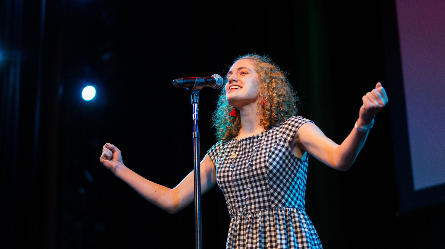 Student performing on stage with a mic