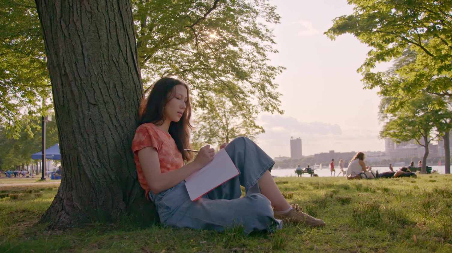 Student writing in a notebook outside